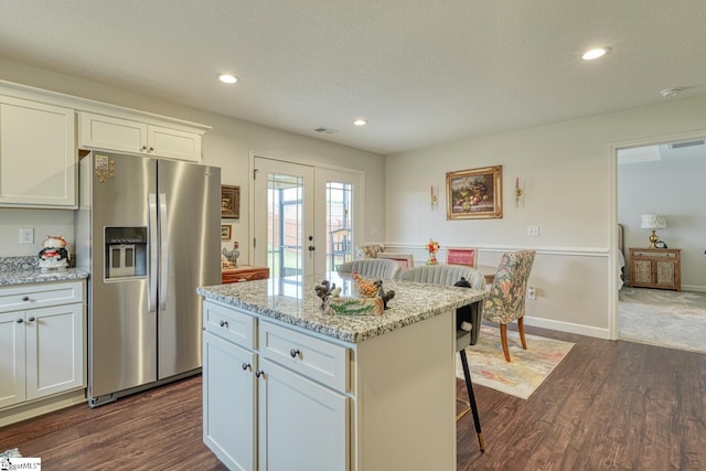 kitchen with dark wood-style flooring, a kitchen breakfast bar, french doors, stainless steel refrigerator with ice dispenser, and visible vents