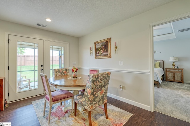dining space with french doors, a textured ceiling, visible vents, wood finished floors, and baseboards