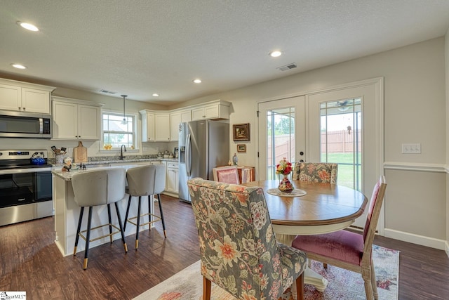 dining room featuring a textured ceiling, dark wood finished floors, french doors, recessed lighting, and visible vents