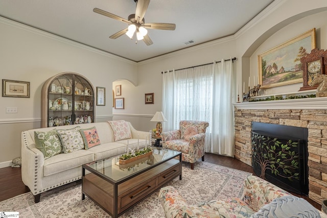 living area with crown molding, visible vents, wood finished floors, a fireplace, and a ceiling fan