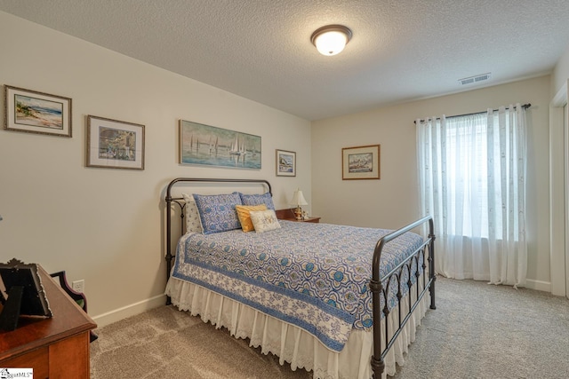 bedroom with visible vents, carpet flooring, a textured ceiling, and baseboards