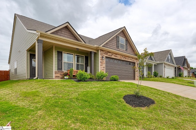 view of front of house with covered porch, driveway, fence, a front lawn, and stone siding