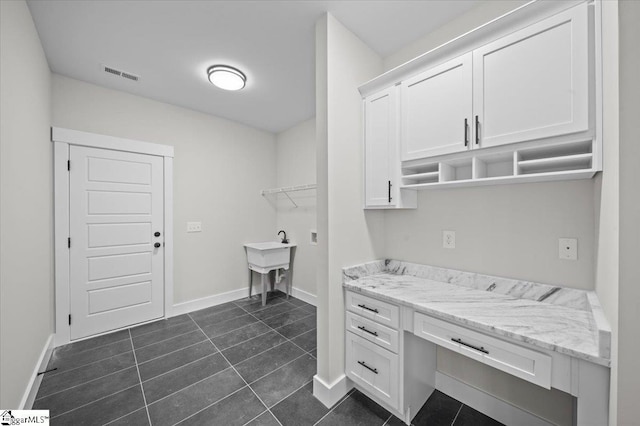clothes washing area featuring visible vents, baseboards, and dark tile patterned floors