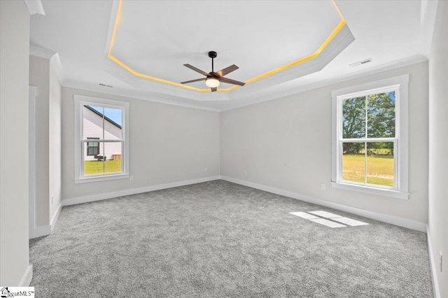 carpeted empty room featuring crown molding, baseboards, ceiling fan, and a tray ceiling