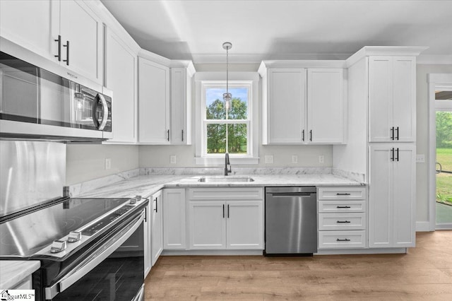 kitchen with a sink, white cabinetry, appliances with stainless steel finishes, and light wood finished floors