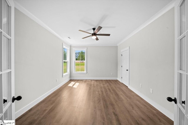 empty room with ornamental molding, wood finished floors, baseboards, ceiling fan, and french doors