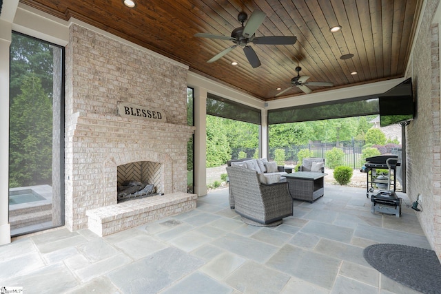 view of patio / terrace featuring a ceiling fan, an outdoor living space with a fireplace, fence, and grilling area