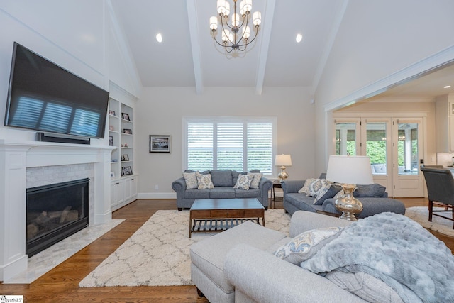 living area with a fireplace with flush hearth, wood finished floors, a chandelier, built in shelves, and lofted ceiling with beams