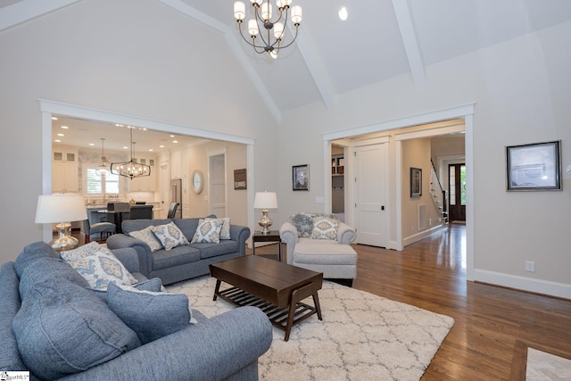 living room with high vaulted ceiling, plenty of natural light, wood finished floors, and a chandelier