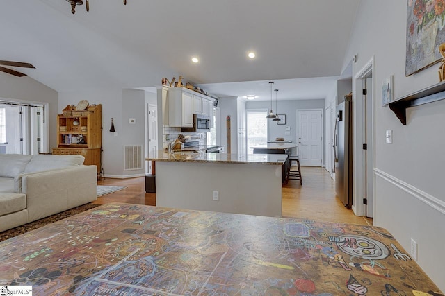 kitchen featuring light stone countertops, light wood-style flooring, stainless steel appliances, a ceiling fan, and visible vents