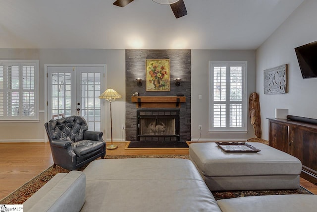 living area with baseboards, ceiling fan, wood finished floors, and a fireplace