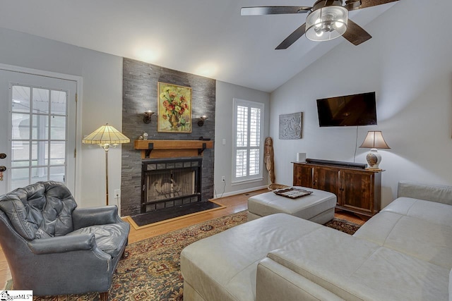 living area featuring a large fireplace, a ceiling fan, vaulted ceiling, and wood finished floors