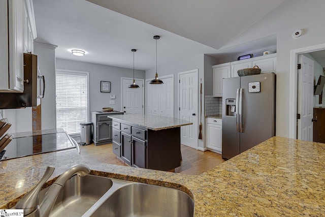 kitchen with light wood-style flooring, stainless steel appliances, decorative light fixtures, white cabinetry, and backsplash