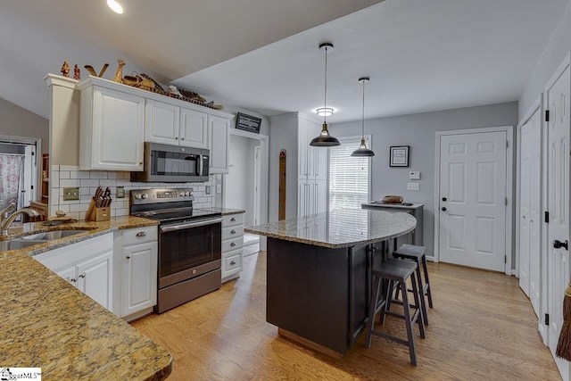 kitchen with decorative backsplash, light stone countertops, white cabinetry, a sink, and appliances with stainless steel finishes