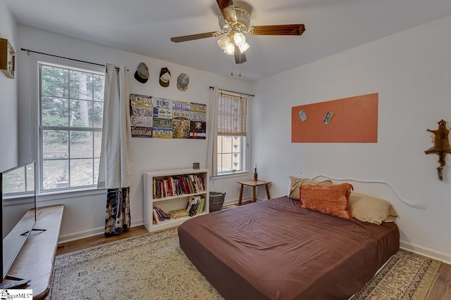 bedroom with a ceiling fan, baseboards, and wood finished floors