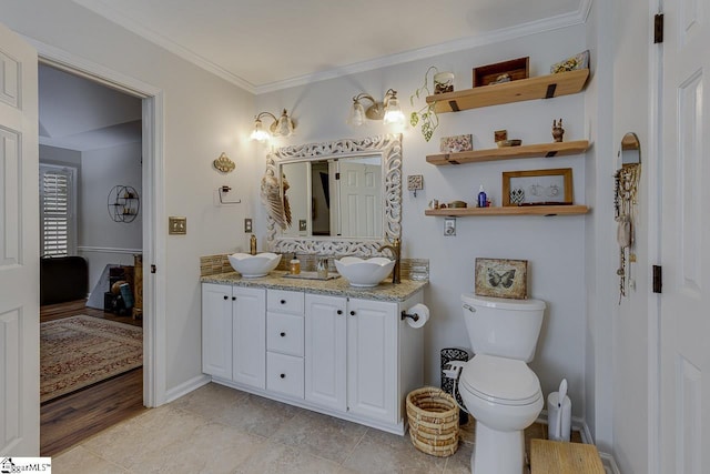 full bath featuring double vanity, ornamental molding, toilet, baseboards, and a sink