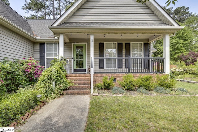 exterior space featuring covered porch, a shingled roof, and a yard