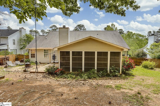 rear view of property featuring fence, roof with shingles, an outdoor fire pit, a sunroom, and a patio area