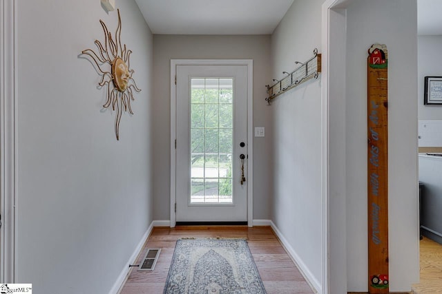 entryway with baseboards, light wood finished floors, and visible vents