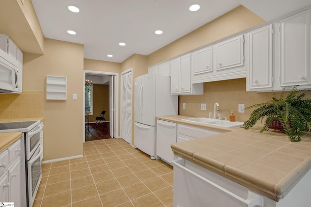 kitchen featuring white appliances, white cabinetry, tile countertops, and a sink