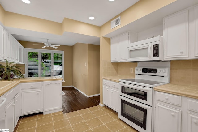 kitchen featuring visible vents, white cabinetry, tile counters, and white appliances