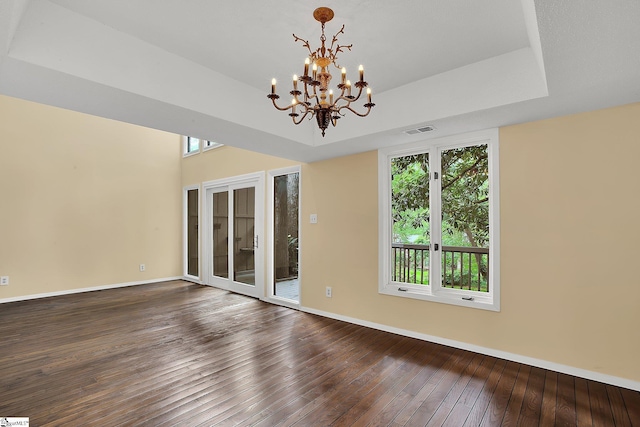unfurnished room with a healthy amount of sunlight, visible vents, hardwood / wood-style floors, and a chandelier