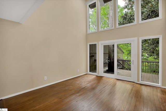 interior space featuring baseboards, a high ceiling, and hardwood / wood-style floors