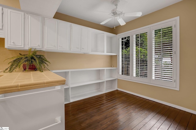 unfurnished room with baseboards, a ceiling fan, and dark wood-style flooring
