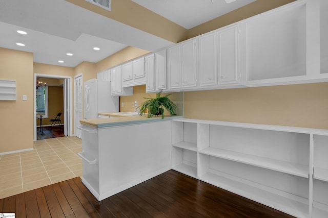 kitchen featuring freestanding refrigerator, a peninsula, recessed lighting, light countertops, and white cabinetry