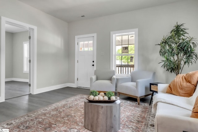 living area with visible vents, baseboards, and wood finished floors