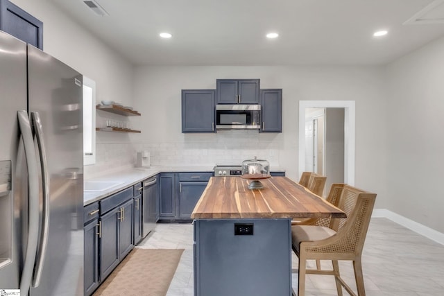 kitchen with open shelves, appliances with stainless steel finishes, a breakfast bar area, wood counters, and backsplash