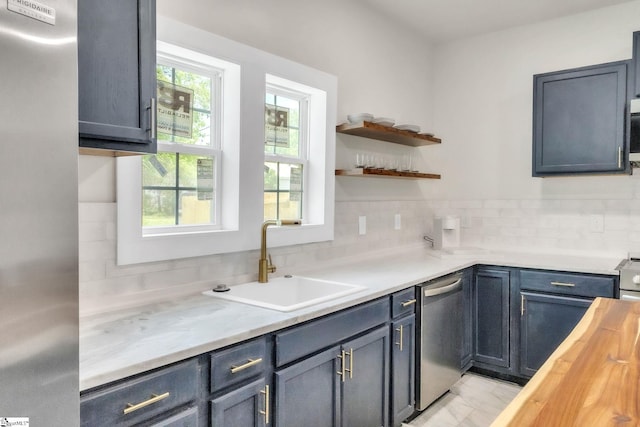 kitchen featuring open shelves, butcher block countertops, a sink, backsplash, and stainless steel appliances