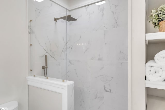 bathroom featuring toilet and a marble finish shower