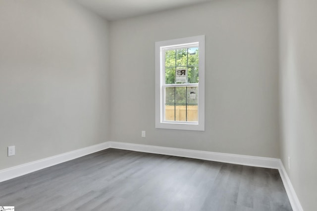 spare room featuring dark wood-type flooring and baseboards