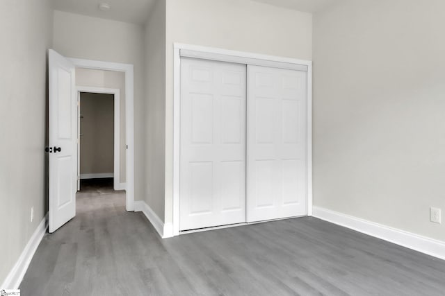 unfurnished bedroom with baseboards, wood finished floors, and a closet