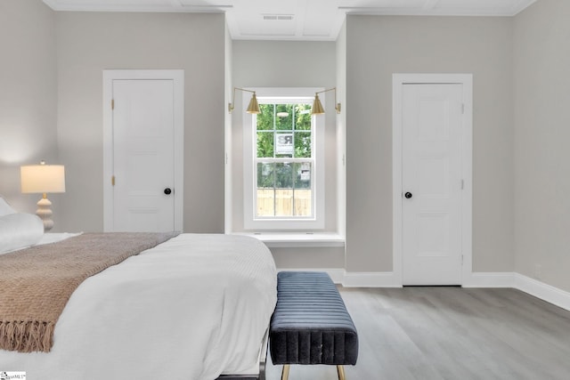 bedroom featuring baseboards, visible vents, ornamental molding, and wood finished floors