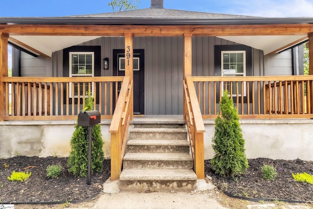 view of exterior entry with covered porch and a chimney