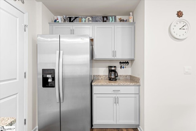 kitchen featuring stainless steel refrigerator with ice dispenser and light stone counters