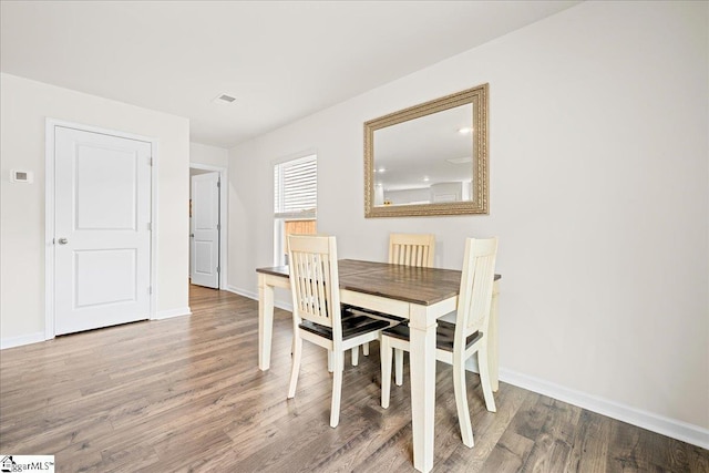 dining space with baseboards and wood finished floors