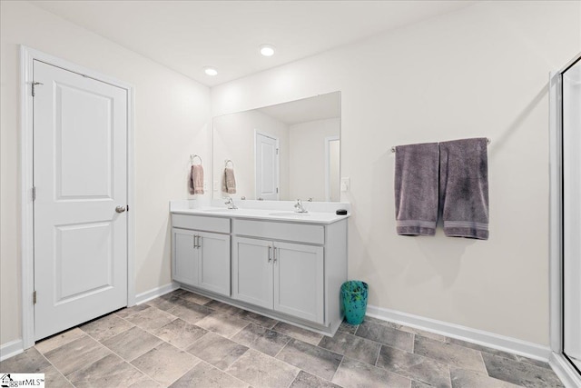 bathroom featuring a sink, baseboards, recessed lighting, and double vanity