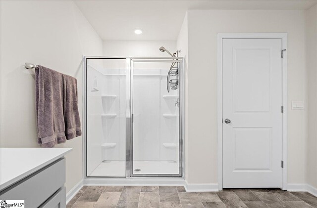full bath featuring vanity, baseboards, a stall shower, and recessed lighting