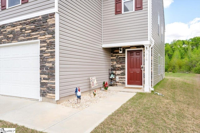 property entrance with an attached garage, a yard, and stone siding