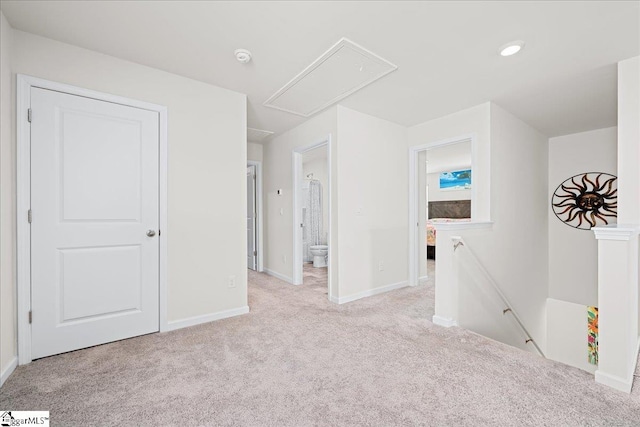 carpeted empty room with baseboards and attic access