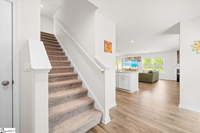 stairway featuring baseboards, a fireplace, recessed lighting, and wood finished floors