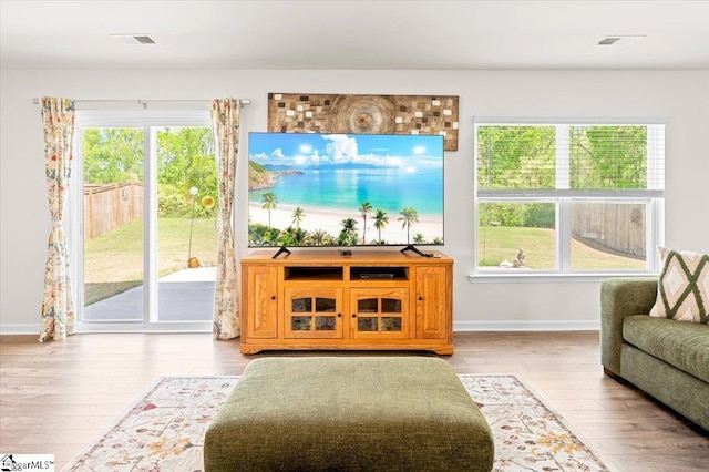 living room featuring baseboards, visible vents, and wood finished floors