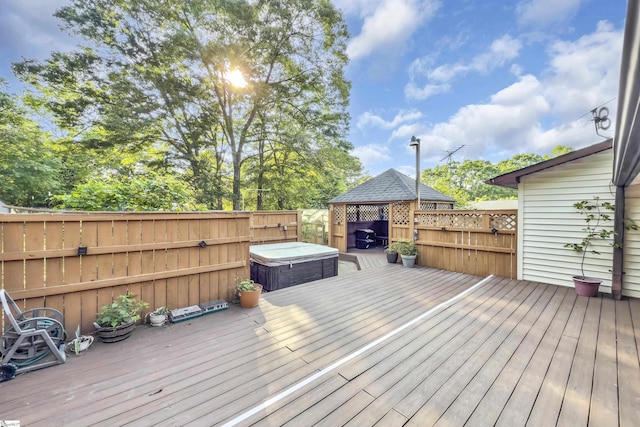 deck with a fenced backyard, a gazebo, and a hot tub