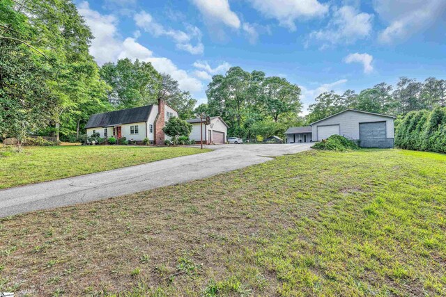 view of front of home with an outdoor structure, a garage, and a front lawn