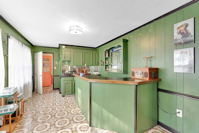 kitchen featuring crown molding, a textured ceiling, light floors, and green cabinets