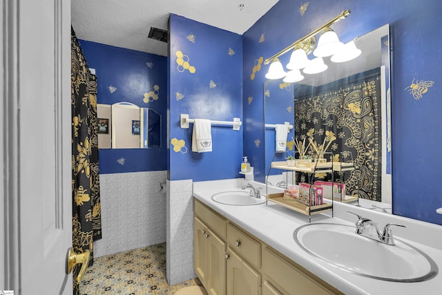 full bath with a sink, wainscoting, and double vanity