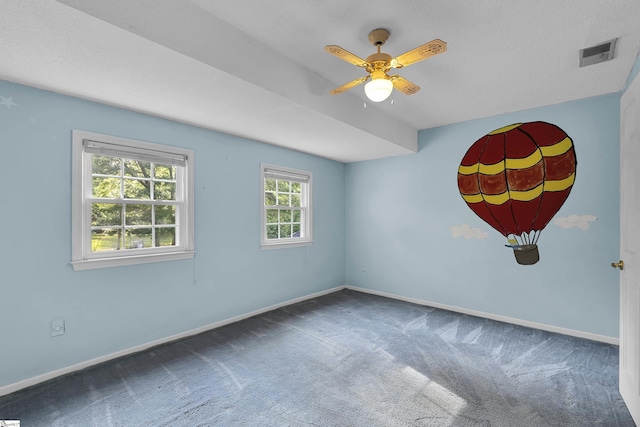 carpeted empty room with visible vents, baseboards, and ceiling fan